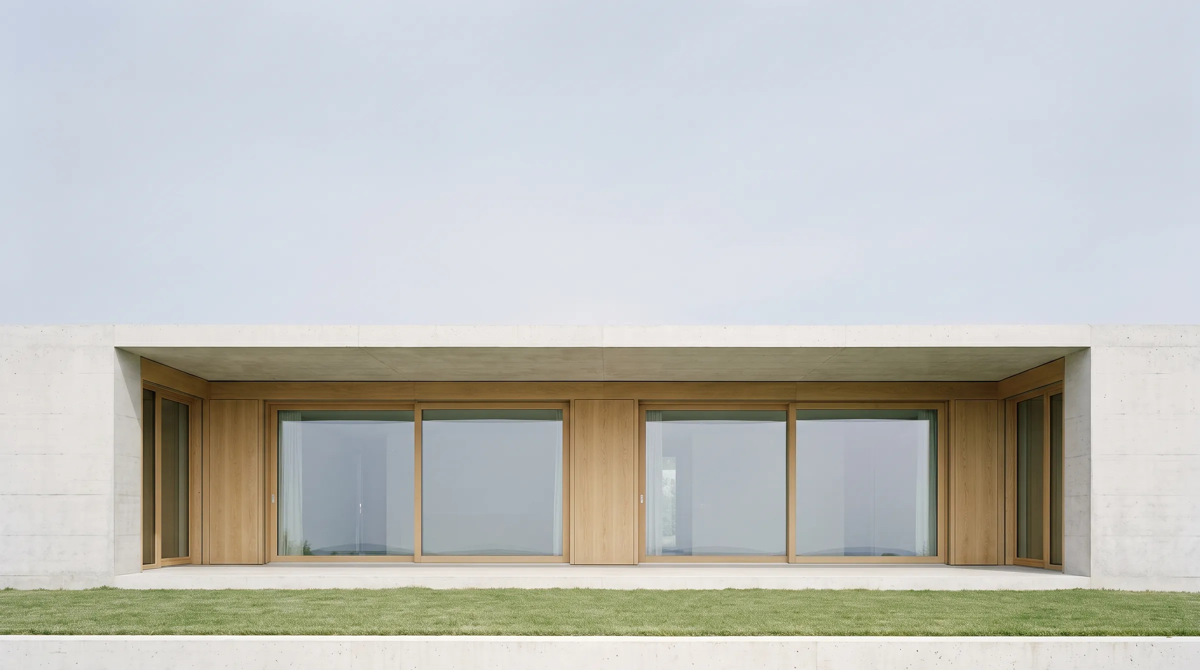 Frontalansicht einer modernen Villa aus Sichtbeton und Eichenholz mit grossen Fenstern